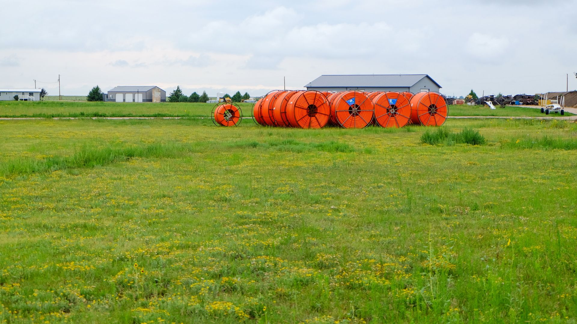 Orange cable for broadband connections on a steel cable drum on a field