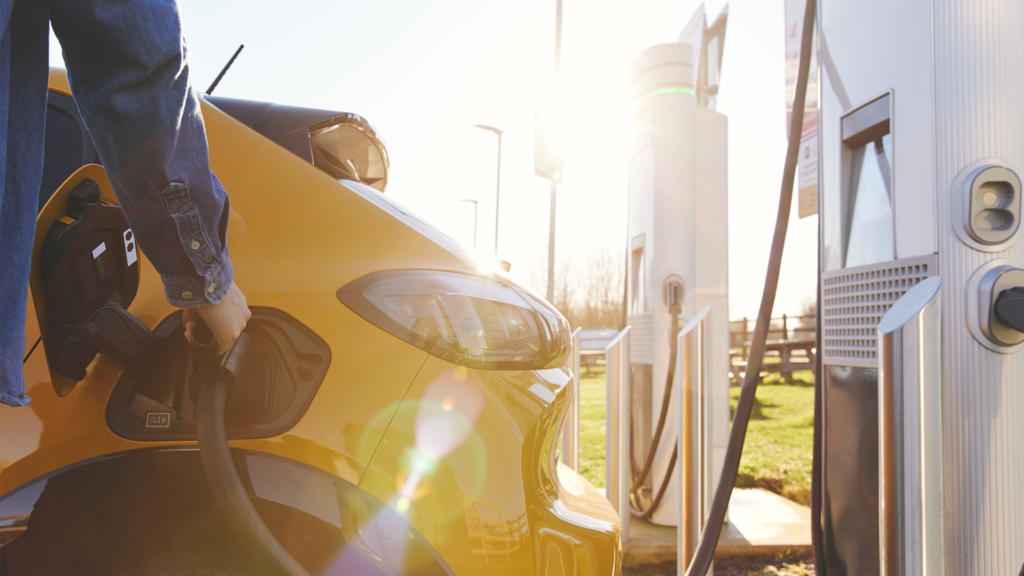 Une personne rechargeant un VE jaune à une station de recharge pour VE