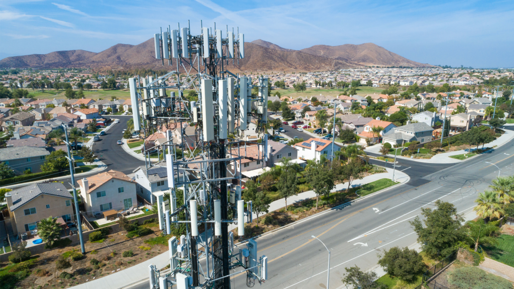 Una torre inalámbrica en una zona suburbana rodeada de montañas al fondo