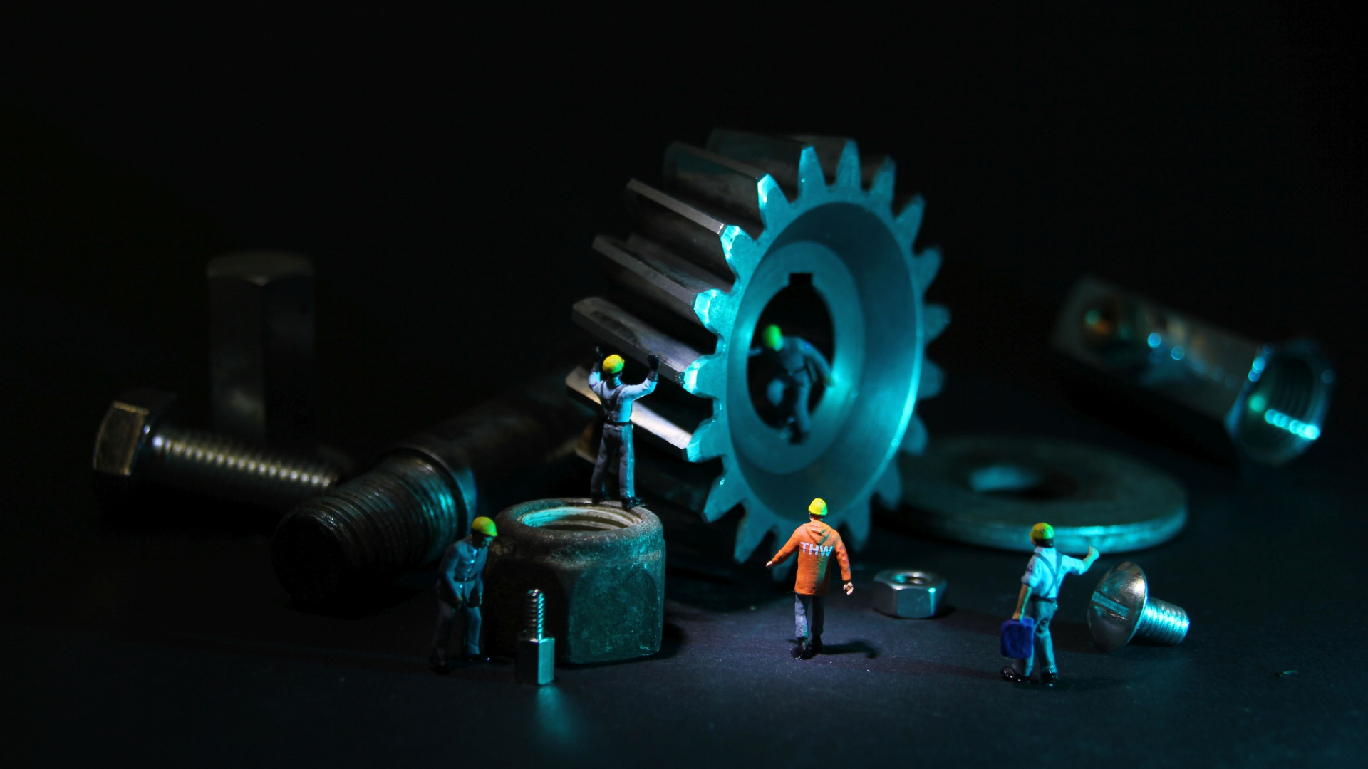 Tiny engineer figures next to tools and gears